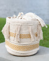 Woven basket with tassels and geometric patterns on a neutral background
