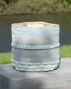Decorative woven basket with striped pattern on a wooden surface outdoors.