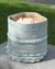 Woven basket with blue, white, and beige stripes on a wooden surface with grass in the background