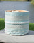 Decorative woven basket with blue and white pattern on a wooden surface near a body of water.