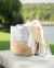 Woven basket with a white and beige blanket on a wooden surface by a lake