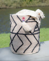 Woven bag with geometric pattern on a surface near a body of water