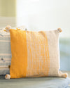 Yellow and white striped pillow on a couch with a blurred background