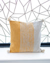 Decorative pillow with yellow and gray pattern on a white surface with geometric wall background