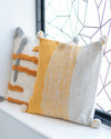 Two patterned pillows on a windowsill with geometric window design in the background