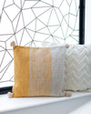 Three decorative pillows with different patterns on a windowsill against a geometric wall.