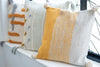 Decorative pillows with yellow and gray patterns on a white surface.