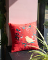 Red pillow with a bird design on a pink wall