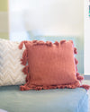 Red pillow with tassels on a light blue couch