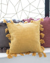 Yellow pillow with tassels on a sofa against a geometric wall design.