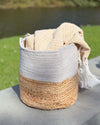 Woven basket with a beige and white fabric on a stone surface with a blurred natural background