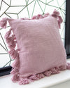 Pink pillow with tassels on a windowsill with a geometric window pattern in the background