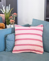 Pink and white striped pillow on a blue sofa with a blurred background