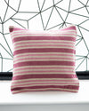 Striped pillow on a white surface with a geometric black and white patterned wall in the background