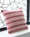 Striped pink and white pillow on a windowsill with a geometric window design in the background.