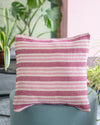 Striped pink and white pillow on a teal chair with plants in the background